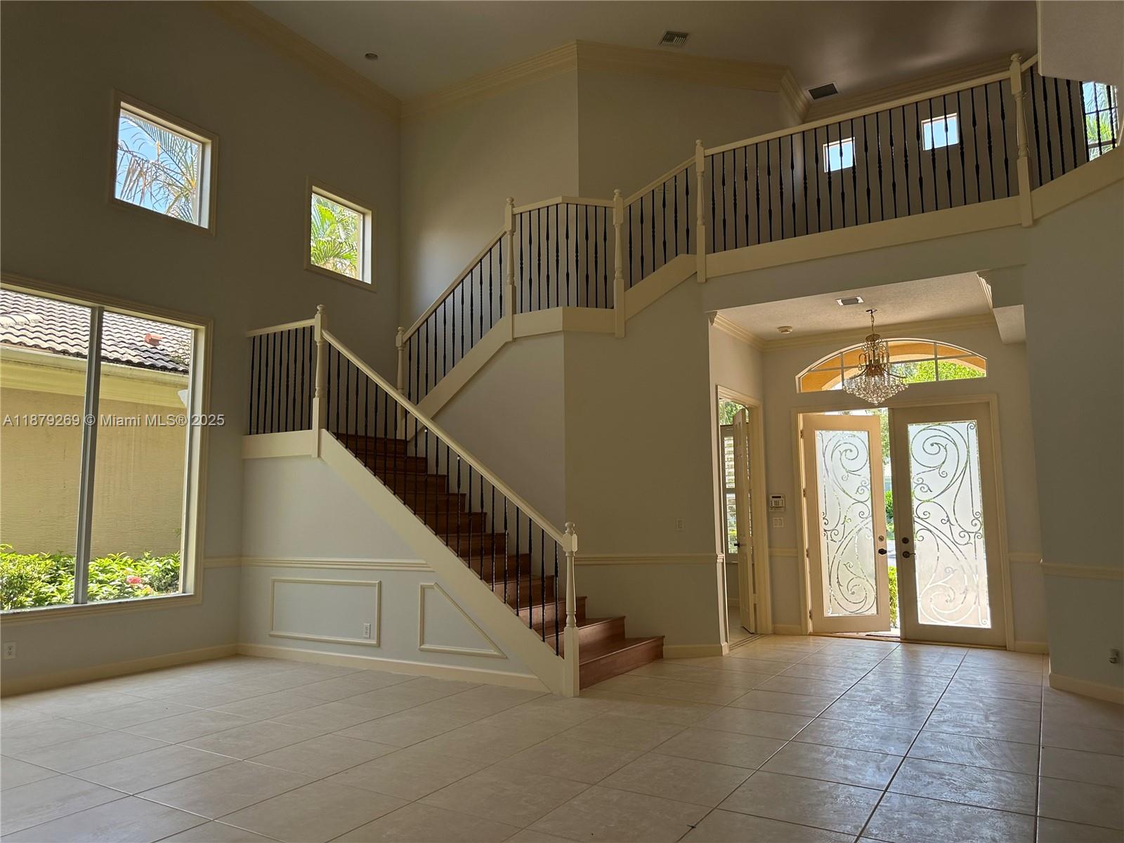 A two-story foyer features a grand staircase, tiled floors, and a decorative glass front door — 138 Tranquilla Dr, Palm Beach Gardens FL 33418, PALM BEACH GARDENS, FL