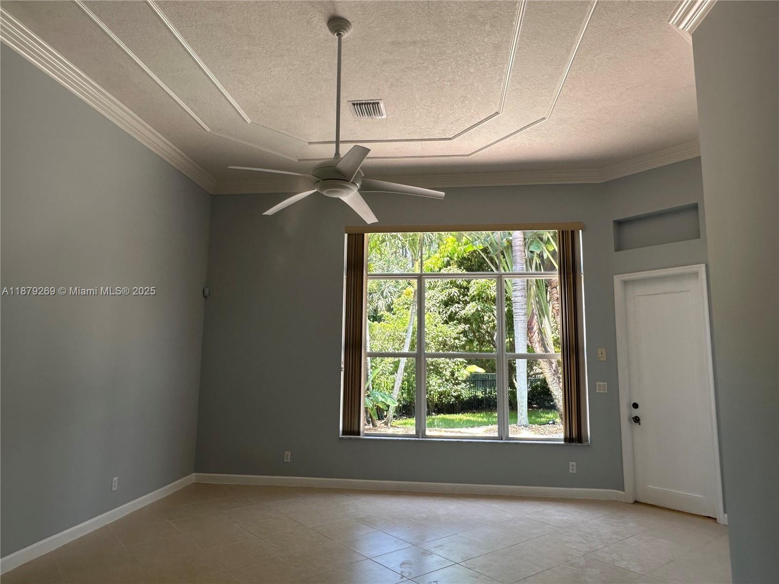 A room with light blue walls, tile flooring, a tray ceiling, and a large window — 138 Tranquilla Dr, Palm Beach Gardens FL 33418, PALM BEACH GARDENS, FL