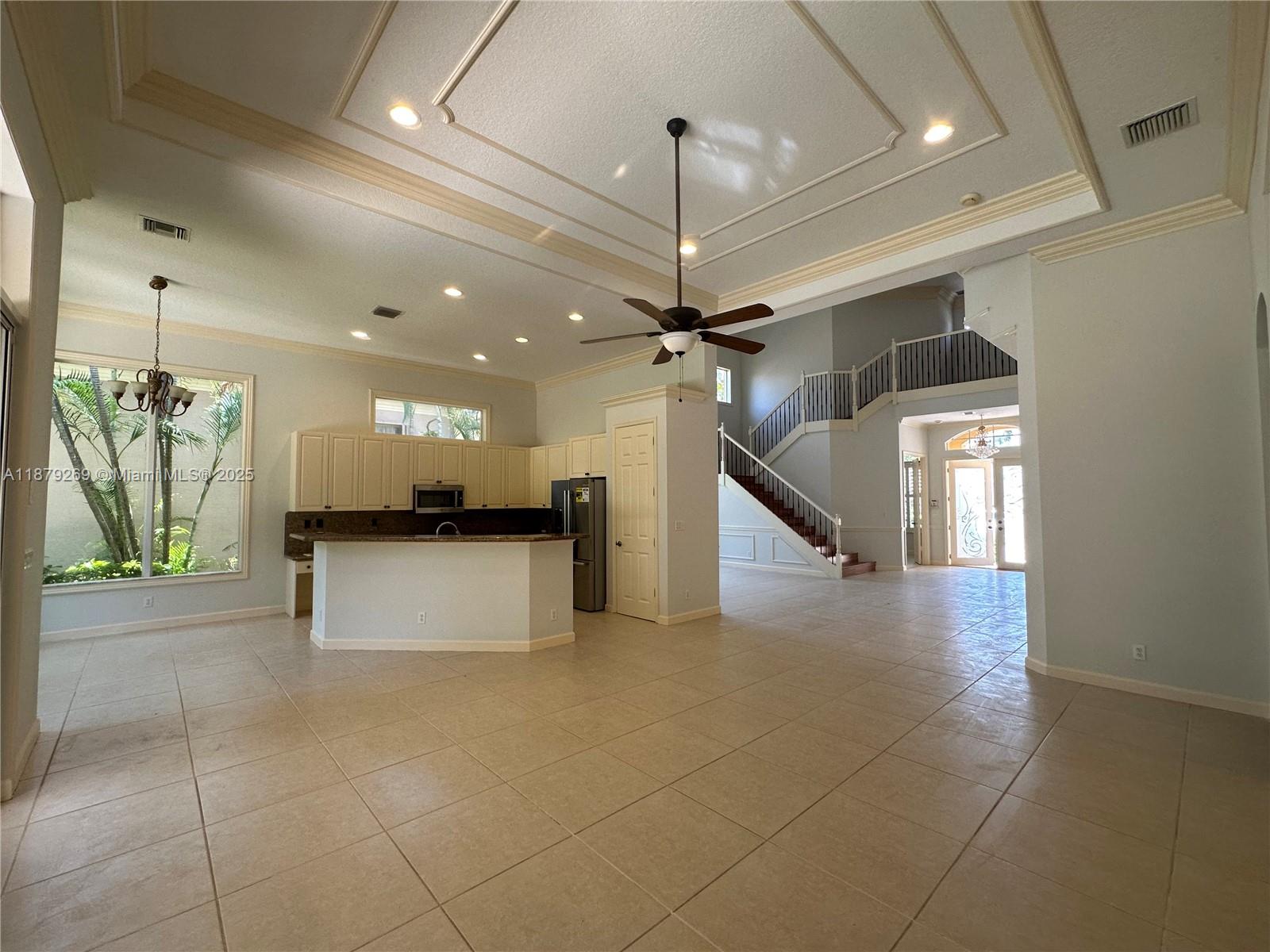 A spacious kitchen with a breakfast bar opens into a large living area with stairs — 138 Tranquilla Dr, Palm Beach Gardens FL 33418, PALM BEACH GARDENS, FL