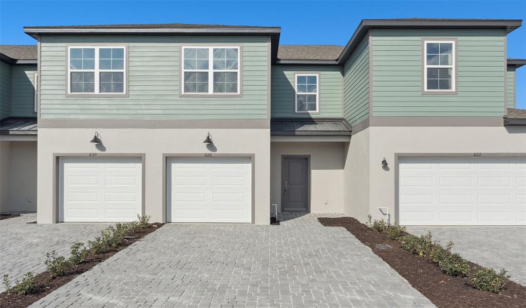 An exterior view of a multi-unit townhouse building with three garage doors and paved driveways — 2298 RED PINE COURT, EUSTIS, FL