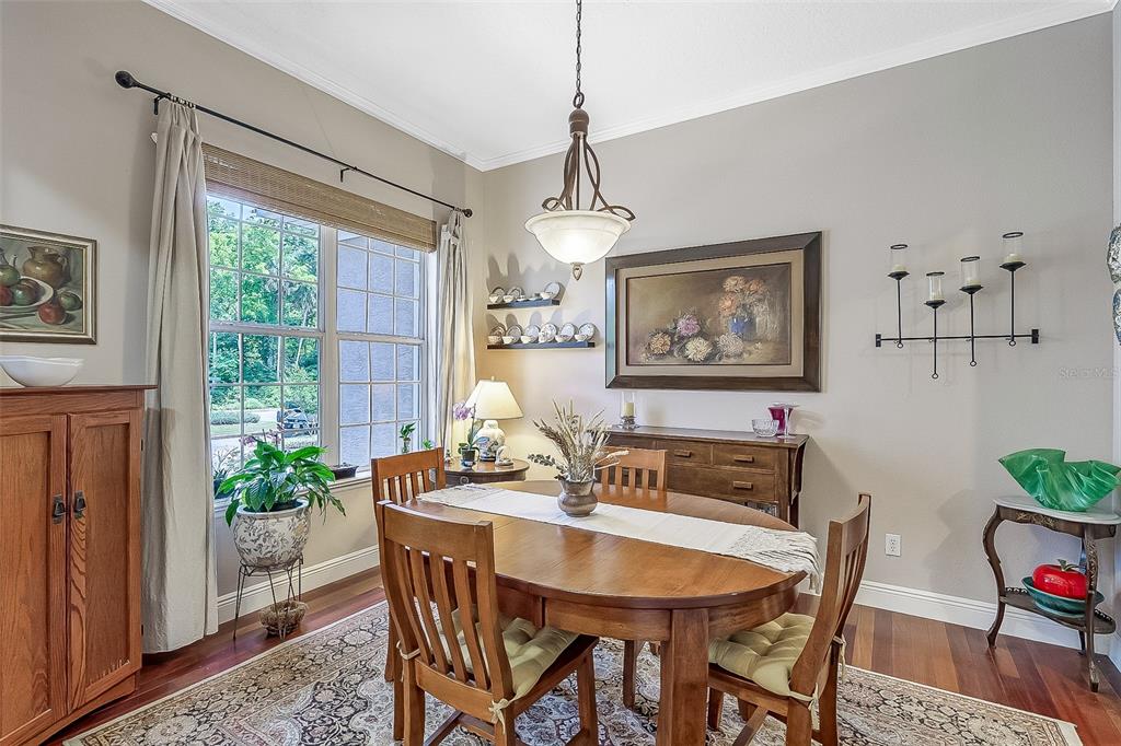 A dining room with a wooden table, chairs, a chandelier, and a large window — 629 RYAN COURT, WINTER SPRINGS, FL