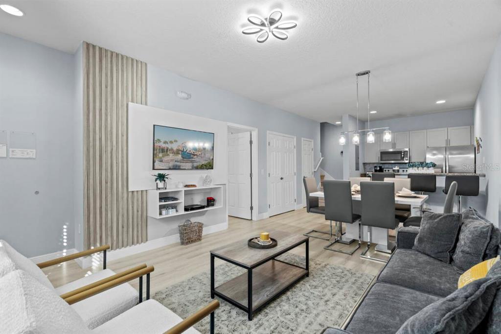 A living room and dining area feature light wood flooring, gray furniture, and a television wall — 3212 OYSTER LANE, KISSIMMEE, FL