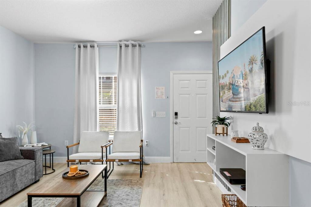 A living room features light wood flooring, a white media console, and two armchairs — 3212 OYSTER LANE, KISSIMMEE, FL
