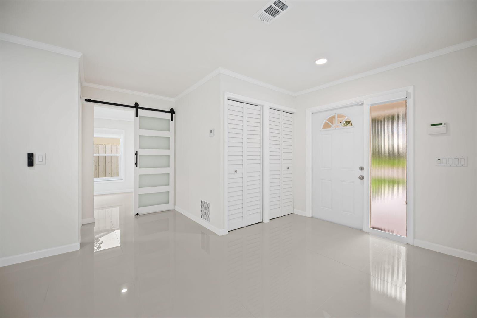 An entryway features white walls, glossy tile flooring, a sliding barn door, and closet doors — 561 SW 168th Terrace, Weston FL 33326, WESTON, FL