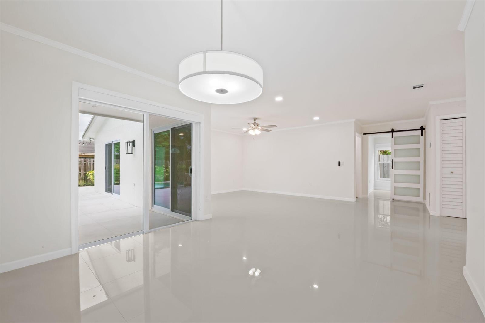 A bright, open-concept room features white tile floors, a modern drum pendant light, and sliding doors — 561 SW 168th Terrace, Weston FL 33326, WESTON, FL