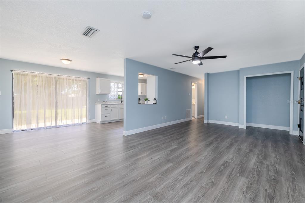 A living room with light blue walls, gray wood-look flooring, and a ceiling fan — 764 REED CANAL ROAD, SOUTH DAYTONA, FL