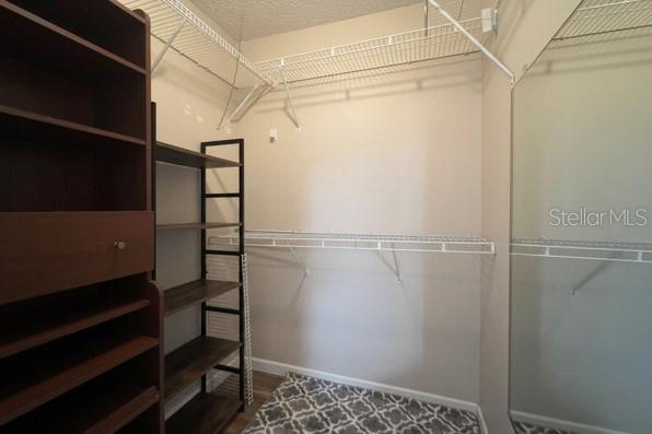 A walk-in closet features wire shelving, a dark wood storage unit, and a patterned rug — 1290 9TH STREET UNIT 506, DAYTONA BEACH, FL