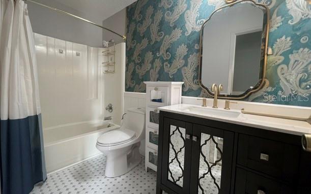 A bathroom features a dark vanity, a patterned blue wallpaper, and a white shower-tub combo — 1290 9TH STREET UNIT 506, DAYTONA BEACH, FL
