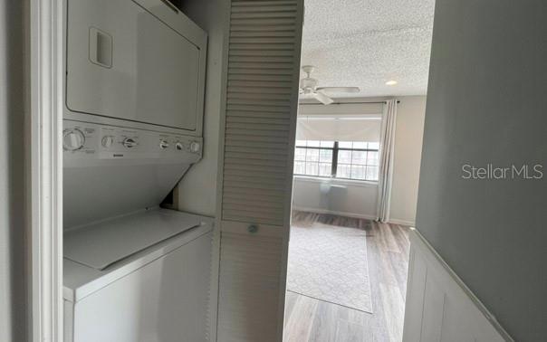 A stacked washer and dryer unit sits in a closet next to a bright living area — 1290 9TH STREET UNIT 506, DAYTONA BEACH, FL