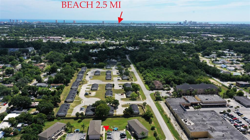 An aerial view shows a residential apartment complex with a nearby commercial building and beach — 1290 9TH STREET UNIT 506, DAYTONA BEACH, FL
