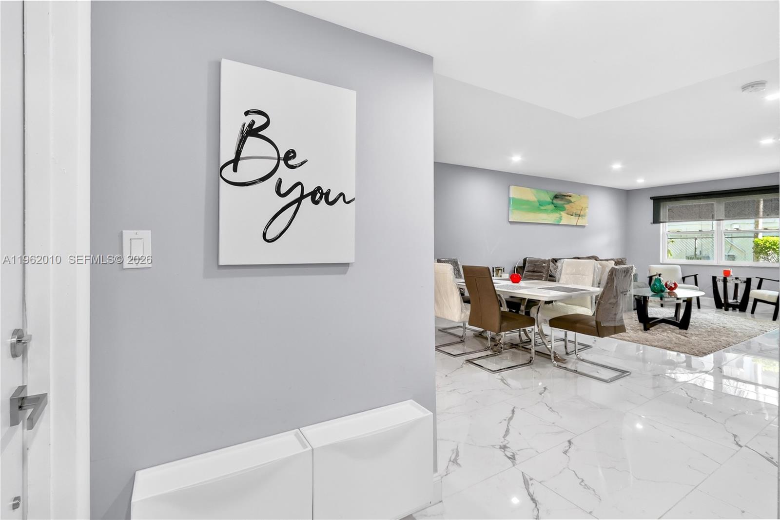 A bright dining and living area features white marble flooring and light gray walls — 410 SE 2nd St # 111, Hallandale Beach FL 33009, HALLANDALE BEACH, FL