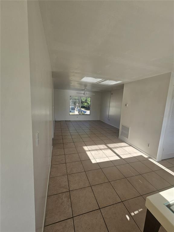 An empty room with light-colored walls and beige tile flooring features a large window — 1709 MICHIGAN AVENUE UNIT C, KISSIMMEE, FL