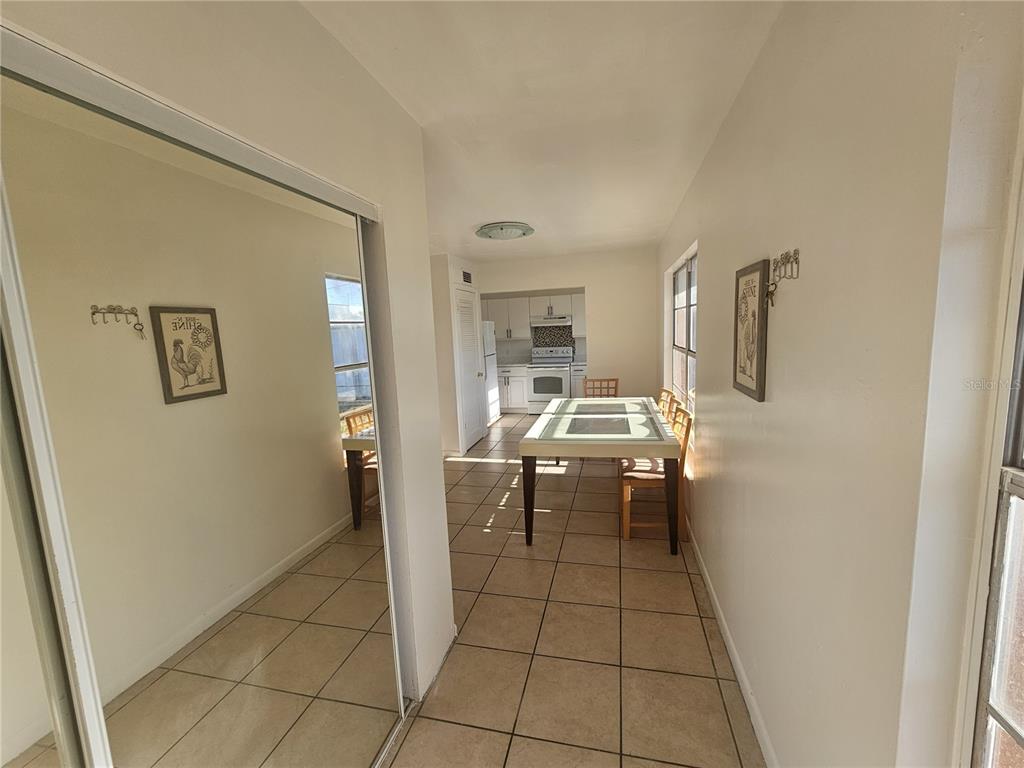 A dining area with tiled floors leads to a kitchen with white cabinets and appliances — 1709 MICHIGAN AVENUE UNIT C, KISSIMMEE, FL