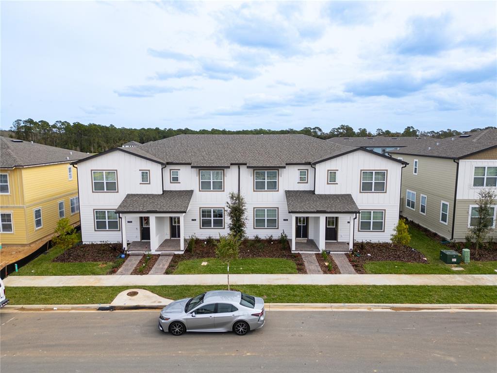 An exterior view of a two-story duplex with white siding and a gray shingled roof — 17741 JAPONICA BLOOM DRIVE, WINTER GARDEN, FL