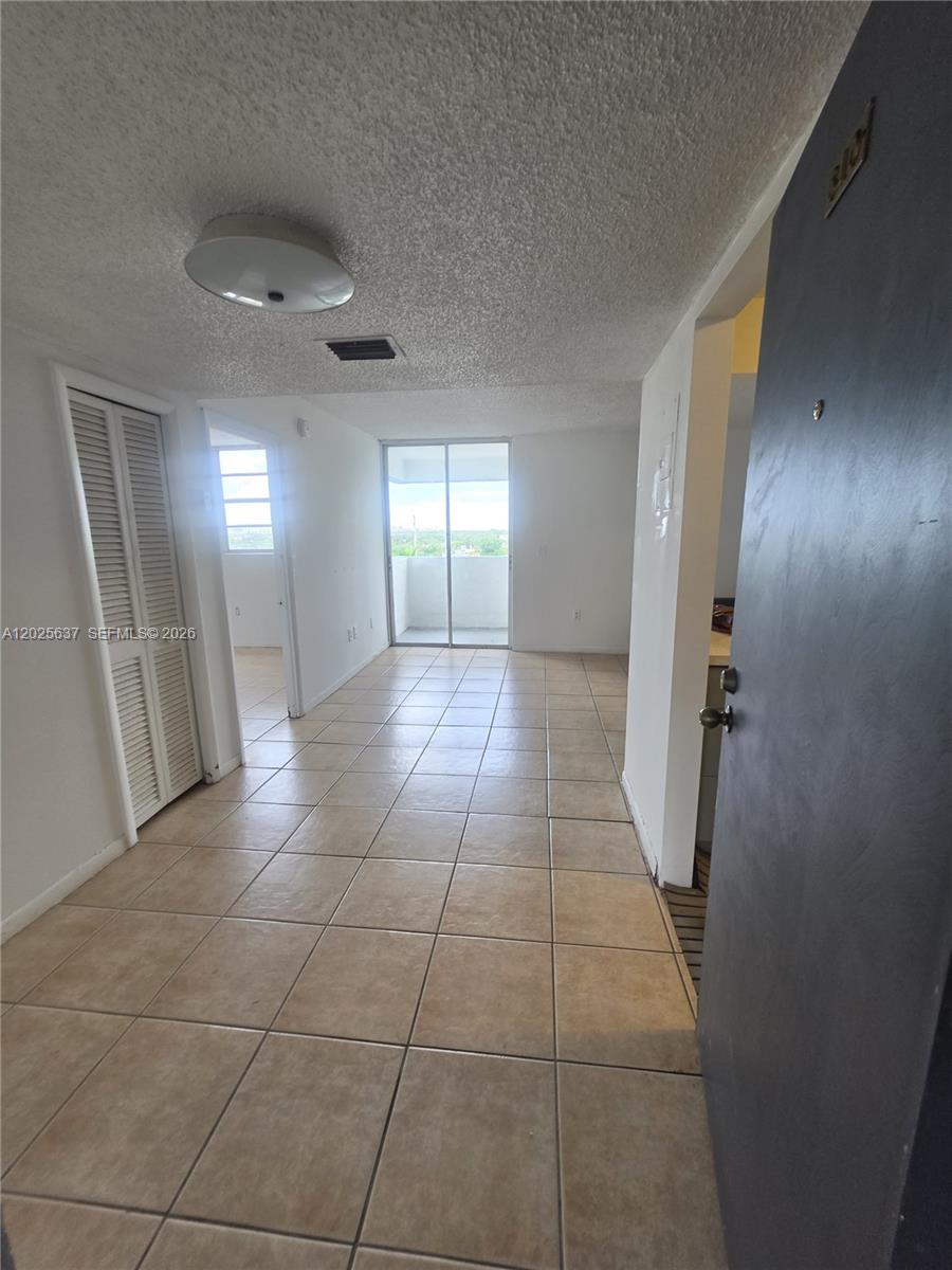 A tiled living area features a white ceiling, a closet, and a sliding glass balcony door — 5050 NW 7th St # 610, Miami FL 33126, MIAMI, FL