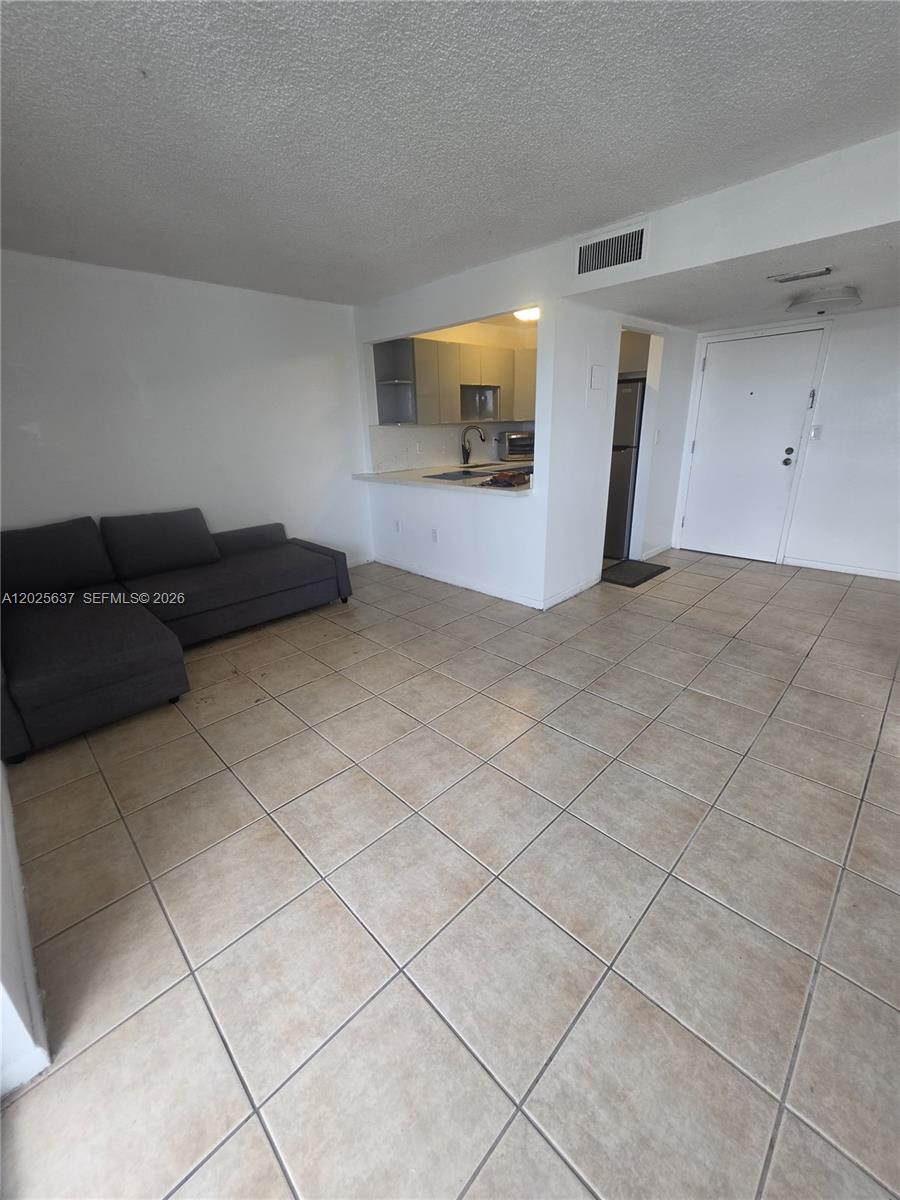 This living room features beige tile flooring, white walls, and an open kitchen pass-through — 5050 NW 7th St # 610, Miami FL 33126, MIAMI, FL