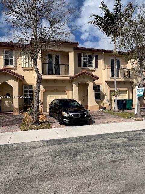 A black sedan is parked in front of a two-story tan townhouse with a balcony — 12923 SW 135th Ter, Miami FL 33186, MIAMI, FL