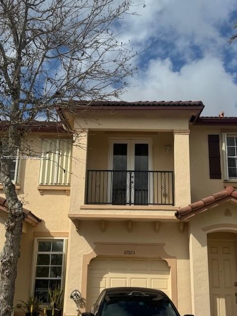 A two-story stucco townhouse features a second-floor balcony with a black metal railing — 12923 SW 135th Ter, Miami FL 33186, MIAMI, FL