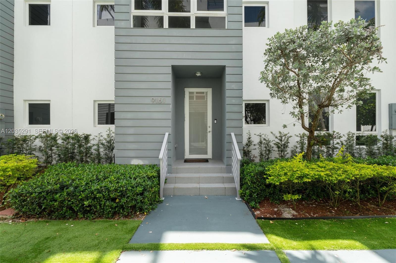 A modern residential building entrance features a gray facade, stairs, and a glass-paneled door — 9161 NW 33rd St, Doral FL 33172, DORAL, FL