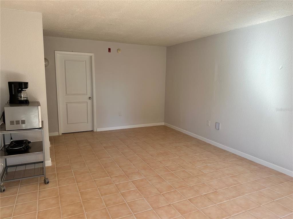 An empty room with light-colored walls, tiled flooring, and a white door — 8421 S ORANGE BLOSSOM TRAIL UNIT 443, ORLANDO, FL