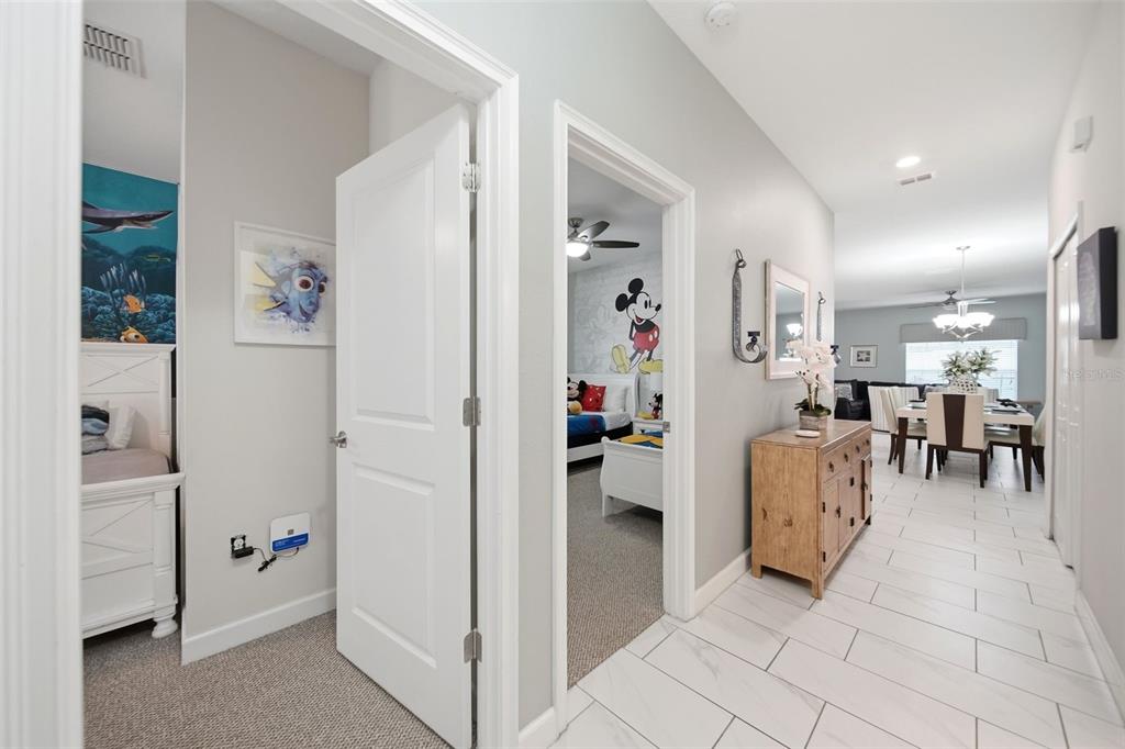 A hallway with white tile floors leads to a dining area, passing two themed bedrooms — 1582 MOON VALLEY DRIVE, DAVENPORT, FL