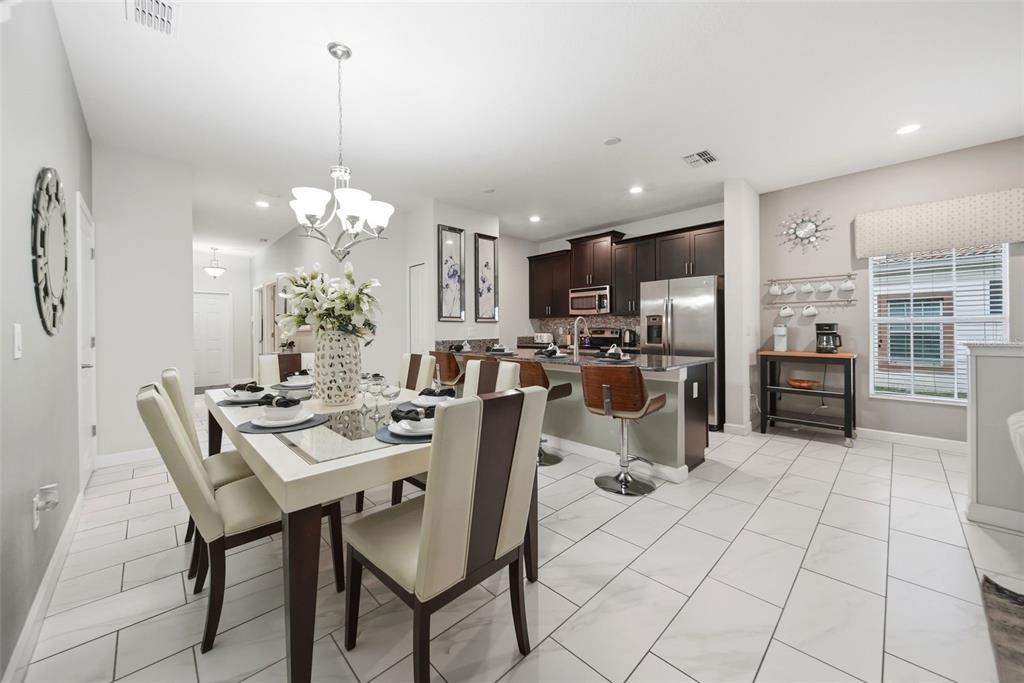 A dining area with a table and chairs opens into a kitchen with dark cabinetry — 1582 MOON VALLEY DRIVE, DAVENPORT, FL