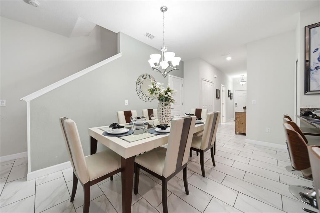 A dining room with a glass-top table, six chairs, and white tile flooring — 1582 MOON VALLEY DRIVE, DAVENPORT, FL