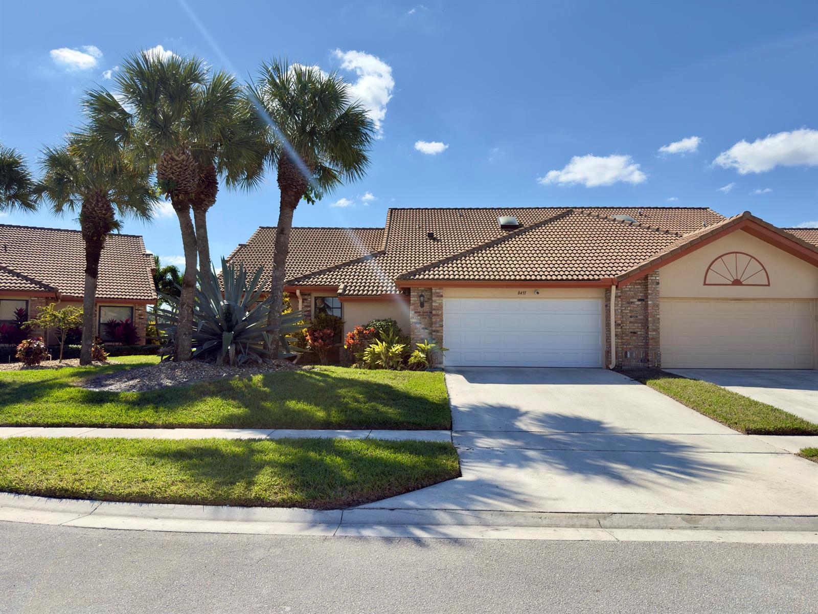 A single-story house with a tiled roof, two garage doors, and palm trees in the yard — 8491 Heather Place, Boynton Beach FL 33472, BOYNTON BEACH, FL