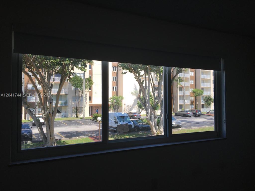 A view of a parking lot and apartment buildings through a large three-pane window — 6930 Miami Gardens Dr # 209, Hialeah FL 33015, HIALEAH, FL