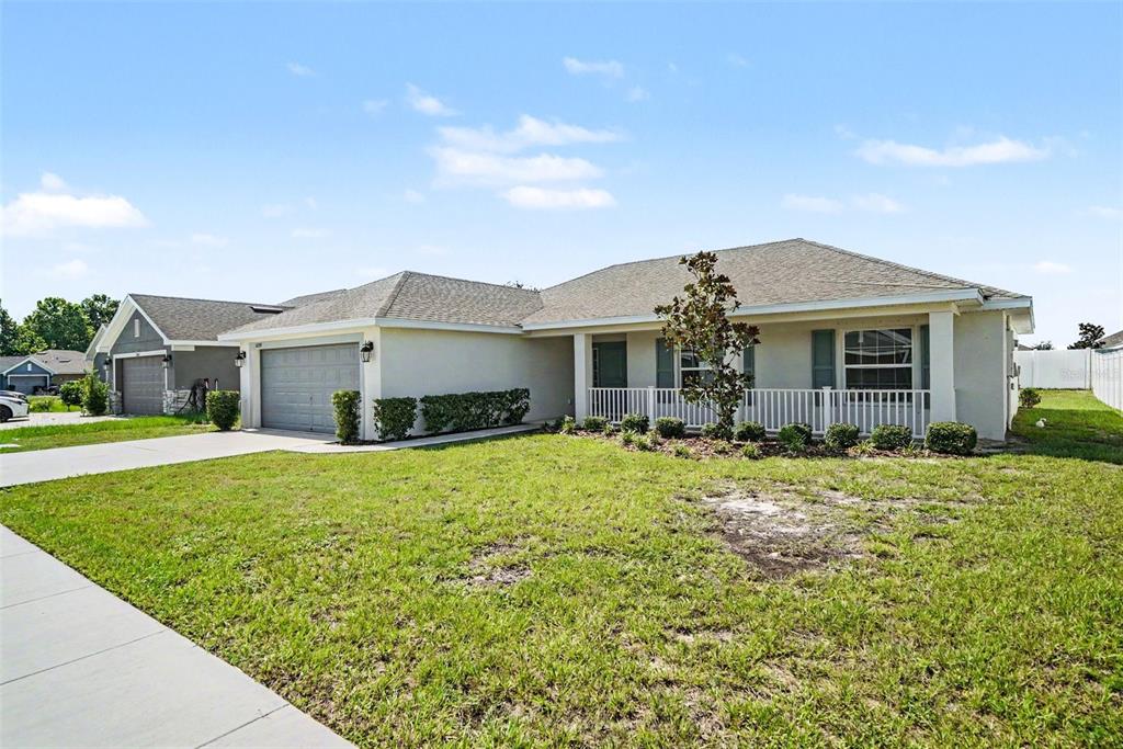 A single-story house with a two-car garage, a front porch, and a grassy lawn — 16253 VINE CLIFF AVENUE, HUDSON, FL