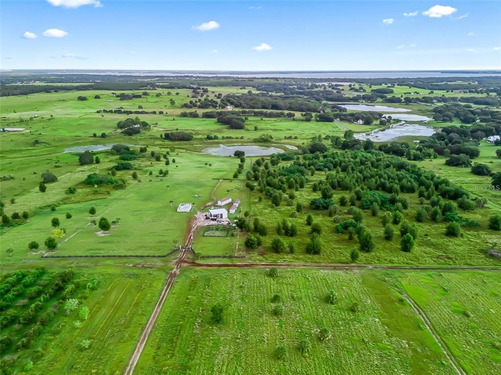 An aerial view shows a rural property with a house, outbuildings, and surrounding pasture land — PUNKIN CENTER ROAD, LEESBURG, FL