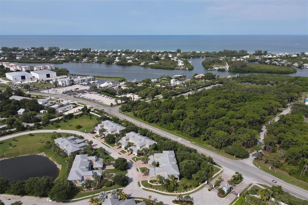 An aerial view shows a coastal neighborhood with multi-family buildings, a road, and vegetation — 10600 LEMON CREEK LOOP UNIT 104, ENGLEWOOD, FL