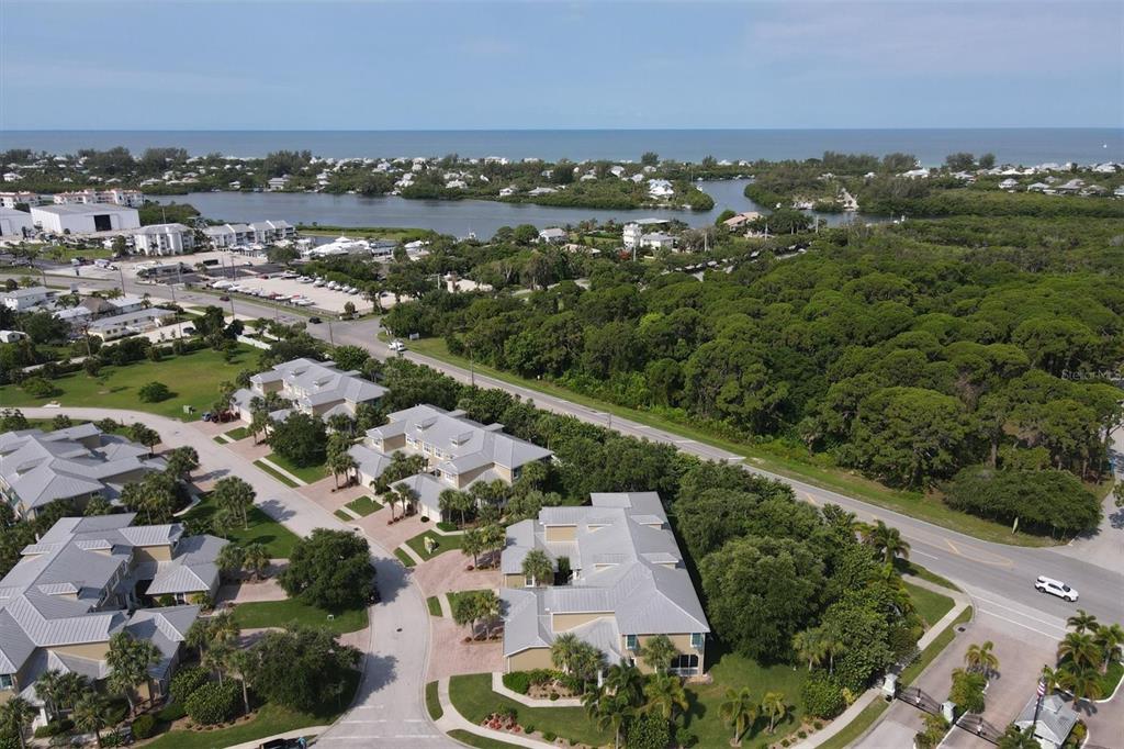 An aerial view shows a residential complex with metal-roofed buildings near a coastal waterway — 10600 LEMON CREEK LOOP UNIT 104, ENGLEWOOD, FL