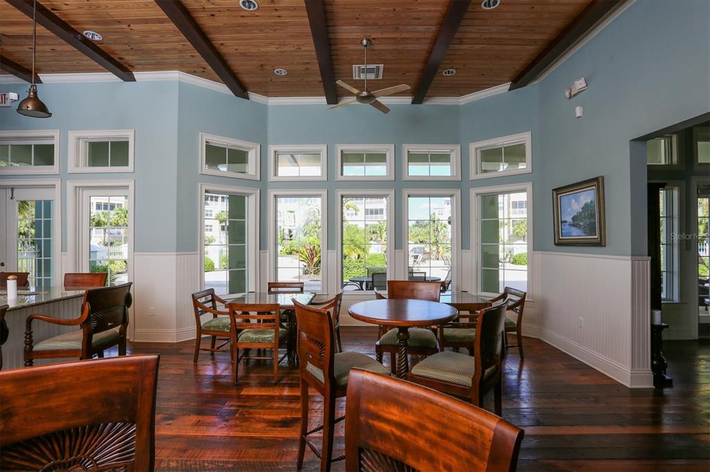 A dining area with wood floors, a wood-paneled ceiling, and large windows overlooking a patio — 10600 LEMON CREEK LOOP UNIT 104, ENGLEWOOD, FL