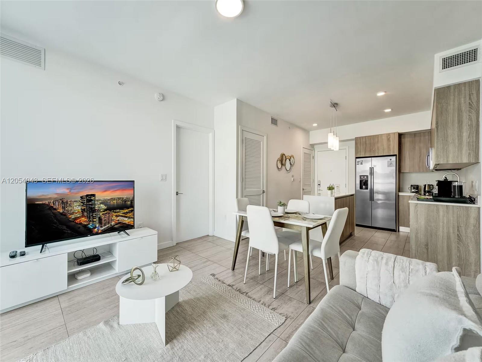 A living room and dining area feature light tile floors, white walls, and wood cabinetry — 3900 Biscayne Blvd # 216, Miami FL 33137, MIAMI, FL