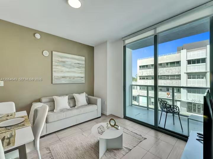 A modern living room features a light gray sofa, a dining area, and a balcony — 3900 Biscayne Blvd # 216, Miami FL 33137, MIAMI, FL