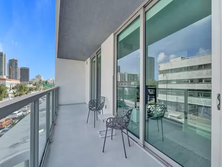 A balcony with two chairs overlooks a city street and surrounding buildings — 3900 Biscayne Blvd # 216, Miami FL 33137, MIAMI, FL