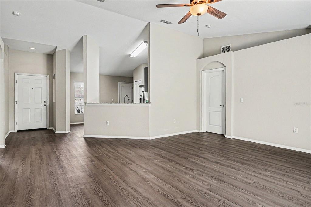 An open living area features wood-look flooring, a ceiling fan, and a kitchen pass-through window — 8187 WOODVINE CIRCLE, LAKELAND, FL