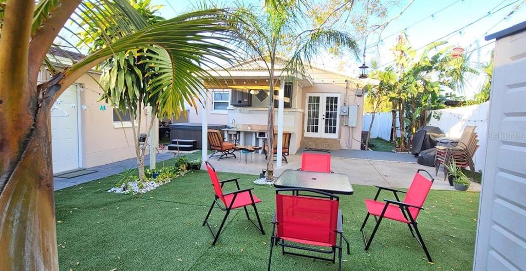 A backyard features a patio with a table, red chairs, and a small outdoor kitchen — 2306 W SAINT JOSEPH STREET, TAMPA, FL