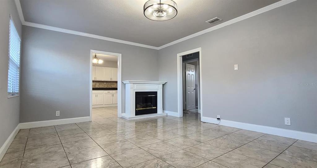 A living room with light gray walls, tile flooring, and a white fireplace — 2306 W SAINT JOSEPH STREET, TAMPA, FL