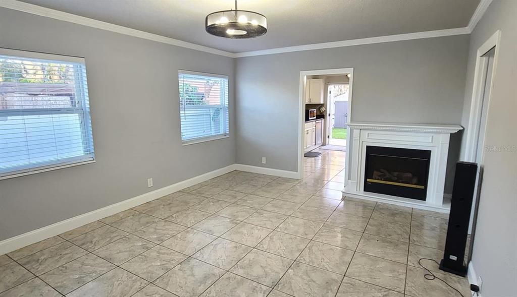 A living room with tile flooring, a fireplace, and a doorway leading to a kitchen — 2306 W SAINT JOSEPH STREET, TAMPA, FL