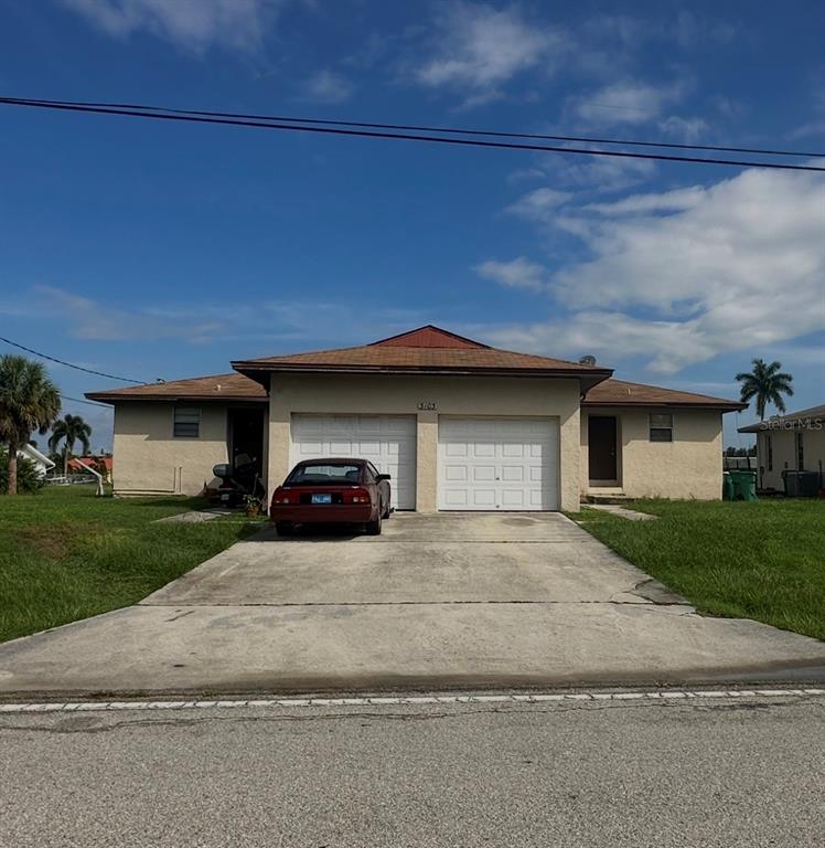 A single-story duplex with a shared concrete driveway and two white garage doors — 3103 RIVERSIDE DRIVE, PUNTA GORDA, FL