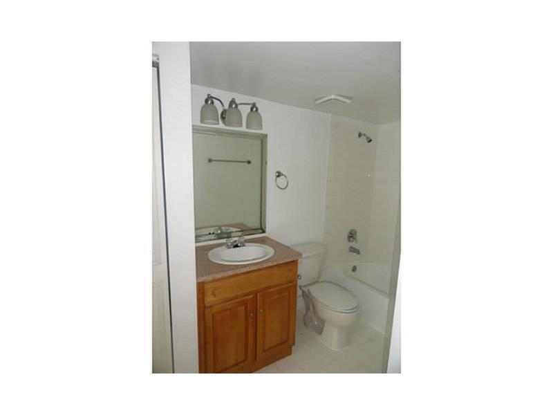 A bathroom featuring a wooden vanity, a sink, a mirror, a toilet, and a bathtub — 12166 Saint Andrews Place # 111, Miramar FL 33025, MIRAMAR, FL