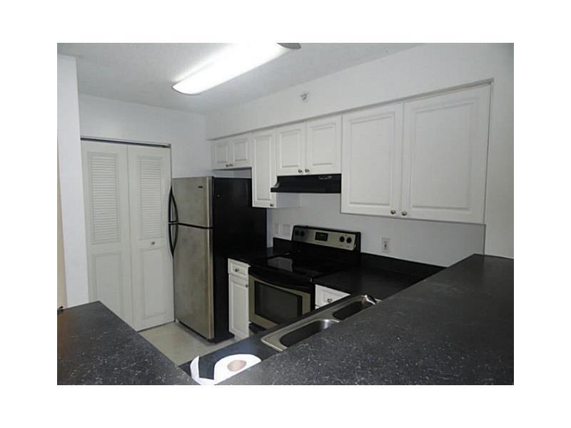 A kitchen features white cabinets, black countertops, stainless steel appliances, and a double sink — 12166 Saint Andrews Place # 111, Miramar FL 33025, MIRAMAR, FL