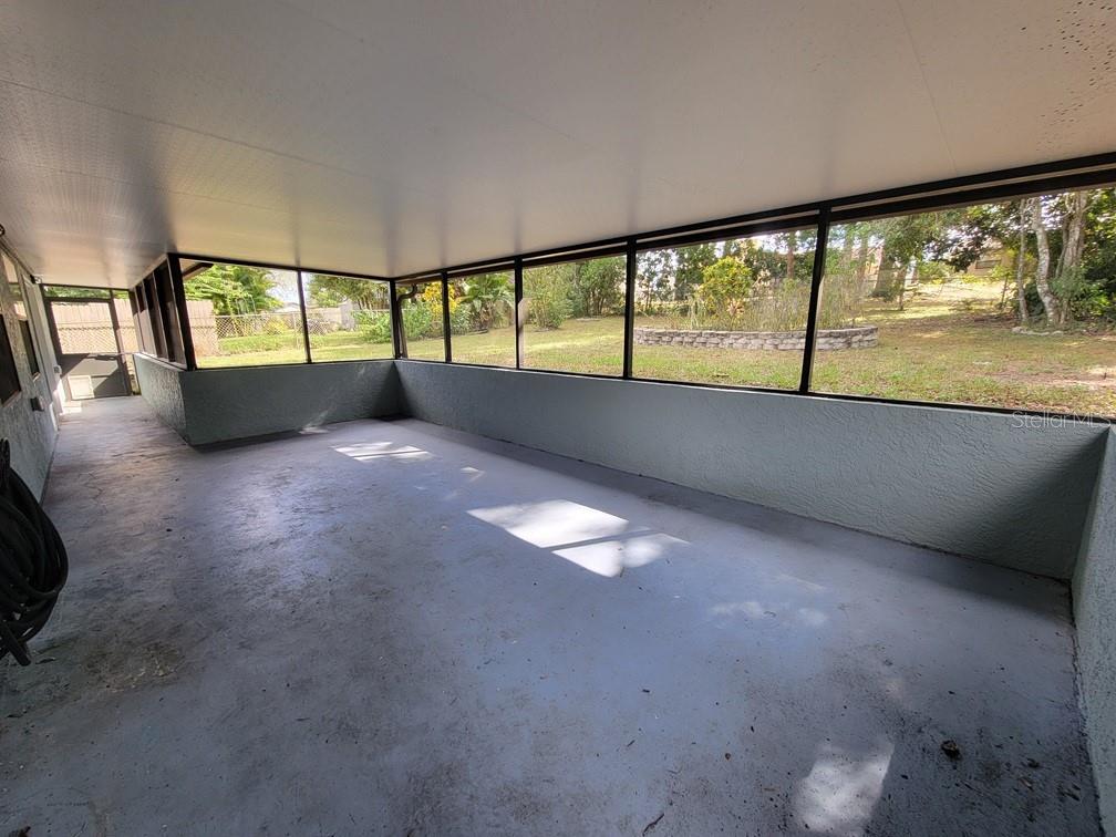 A screened-in porch with a painted concrete floor and views of a grassy backyard — 11633 FOX RUN, PORT RICHEY, FL