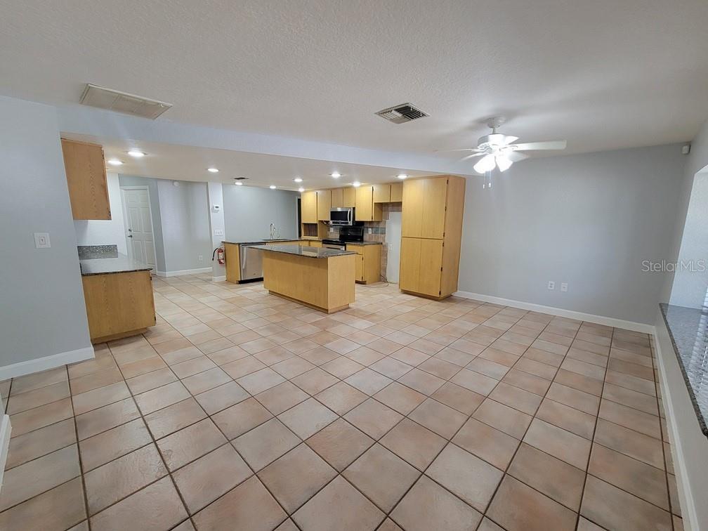 A kitchen with light wood cabinets, a center island, and tile flooring in an open space — 11633 FOX RUN, PORT RICHEY, FL