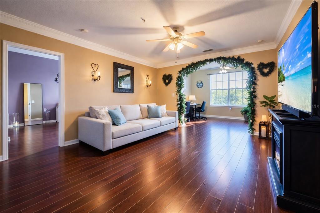 A living room with hardwood floors, a light-colored sofa, and an arched entryway with greenery — 12849 MADISON POINTE CIRCLE UNIT 307, ORLANDO, FL