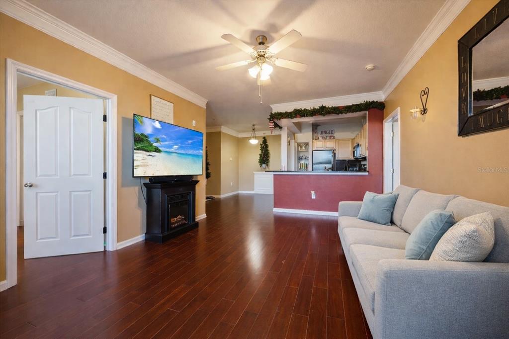 A living room with hardwood floors, a gray sofa, and a television above a fireplace — 12849 MADISON POINTE CIRCLE UNIT 307, ORLANDO, FL