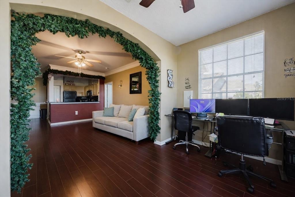 A room with dark wood floors, a sofa, and a desk area under an arched entryway — 12849 MADISON POINTE CIRCLE UNIT 307, ORLANDO, FL