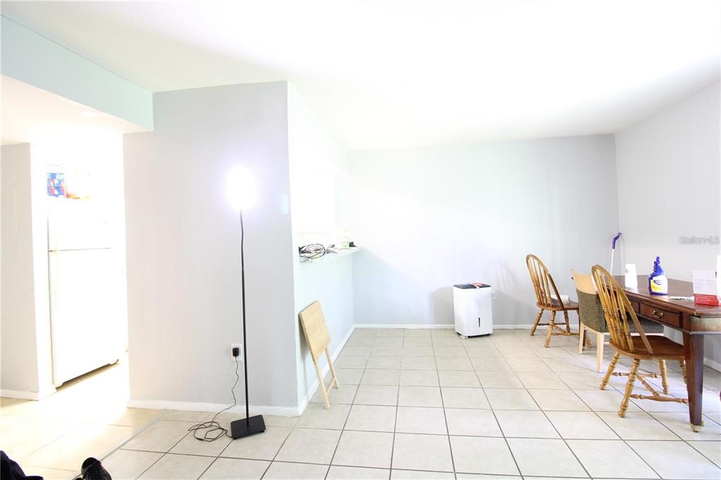 A dining area with tile flooring, a wooden table, chairs, and a floor lamp — 311 SCOTTSDALE SQUARE UNIT 311, WINTER PARK, FL